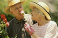 Casal de idade partilhando um momento de felicidade. Homem a cheirar uma rosa.