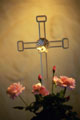 Grande plano de uma rosa, arranjo de flores junto de uma cruz
