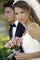 Casal recém-casado fotografado de perfil. Noiva com um ramo de flores rosa.