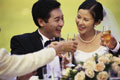 Casal recém-casado brindando com floutes de champanhe. Arranhos de flores de casamento na mesa